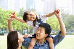 両親と女の子の家族、女の子が笑顔で肩車されている