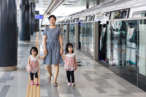 女の子二人を連れて電車のホームに立つ女性